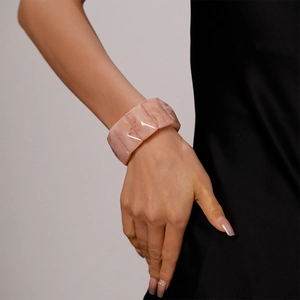Detail of wide acrylic cuff bracelet with pink marble texture on a woman wrist