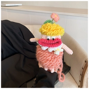 Detail of a handmade pink crochet monster bag with yellow horns and red lips for kids