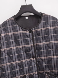 Détail de la veste matelassée à carreaux gris avec col, étiquette XS et boutons noirs