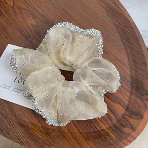 Macro detail of champagne organza scrunchie with white pearl and rhinestone trim