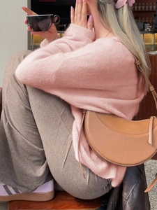 Rosa Strickpullover und braune Leder-Halbmondtasche in gemütlicher Café-Atmosphäre
