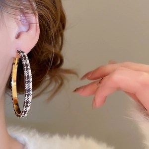 Gros plan sur une boucle d'oreille créole géométrique en tissu à carreaux et métal doré