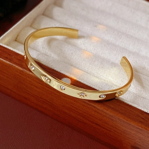 Détail d'un bracelet doré avec motifs d'étoiles gravés et pierres de zircone scintillantes