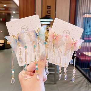 Handheld view of handmade blue and pink butterfly hair clips with beaded tassels and charms