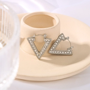 Silver geometric rhombus earrings with cubic zirconia inlay on beige ceramic stand