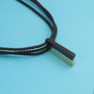 Close-up of triple layered woven leather cords with black, silver, and gold bar pendants