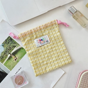 Detail of yellow plaid drawstring storage bag with pink cord and cartoon sunny day label
