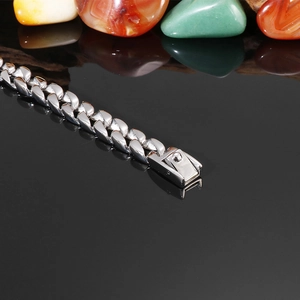 Détail d'une chaîne gourmette argentée avec fermoir carré sur surface noire réfléchissante