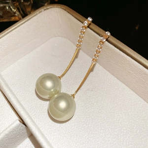 Detail of long pearl drop earrings with sparkling zircons in a beige jewelry box