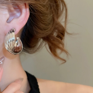 Detailed close-up of layered silver hoop earrings worn on a model in minimalist style