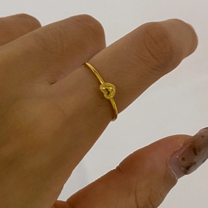 Close-up of a delicate gold heart ring worn on finger with textured beaded edge detail