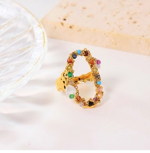 Detail of irregular gold titanium ring with colorful gems and a pearl on stone