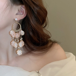 Detail view of gold petal earrings with tassels and pearls on a model ear