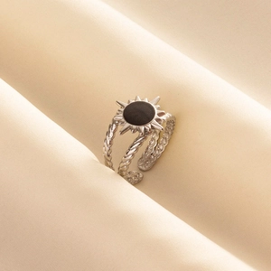 Detail of silver sun ring with black center and twisted rope band on silk