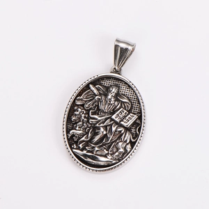 Macro shot of silver oval book pendant with detailed religious character relief carving