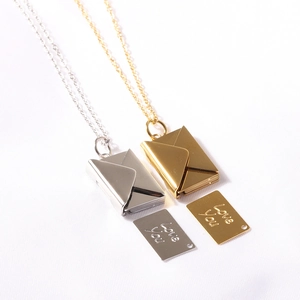 Detailed view of gold and silver envelope necklaces with Love You engraved inner plates