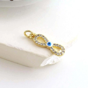 Macro detail of infinity evil eye charm featuring gold plating and white zircon crystals