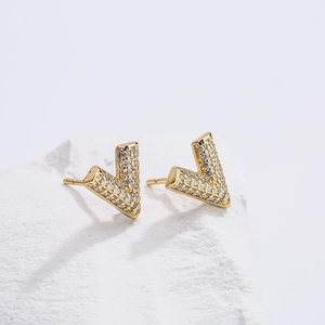 V-shaped 18K gold plated copper earrings with zircon stones on white stone base