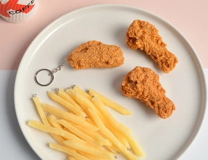 Macro shot of realistic PVC fried chicken wings and fries keychain models on a plate