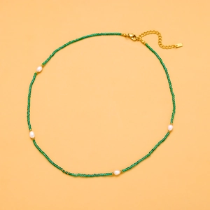 Close-up of green beaded necklace with white pearls and gold-plated lobster clasp
