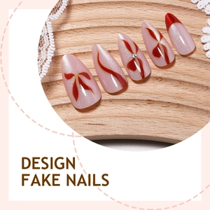 Red cat-eye almond press-on nails with bow design and rhinestone accents on wood tray