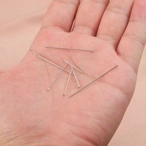 Flat head stainless steel pins for DIY jewelry making held in hand over pink fabric