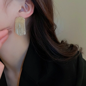 Minimalist metallic fringe earrings with vertical texture shown on a female model