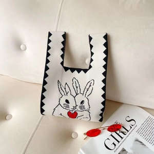 White knit tote bag with black zigzag edge featuring bunny and red heart patterns