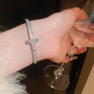 Gros plan d'un bracelet ouvert en forme de T argenté serti de pavé sur le poignet d'une femme