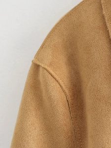 Detailed close-up of stitching and suede texture on a tan fashion jacket shoulder