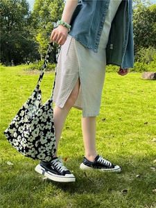 Floral print tote bag shown in an outdoor setting featuring a black and white flower pattern
