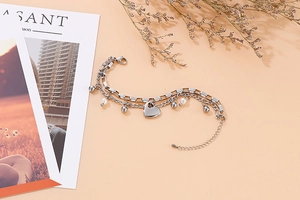 Détail d'un bracelet double rang en acier inoxydable avec charmes cœur et perles blanches