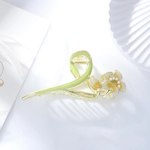 Close-up of a lily flower hair claw clip with green enamel petals and pearls