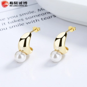 Close-up of golden C-shaped pearl earrings with elegant minimalist crescent design