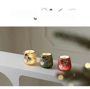 Close-up of three glass Christmas candle holders with festive charms and pine accents