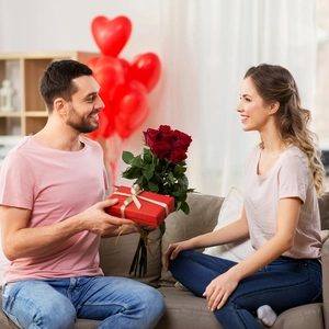 Romantic gift set featuring a red ribbon gift box and fresh roses for couples