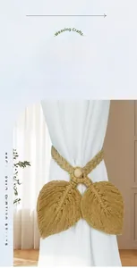 Detail of hand-woven bohemian leaf curtain tieback with cotton rope and wooden bead on white curtain