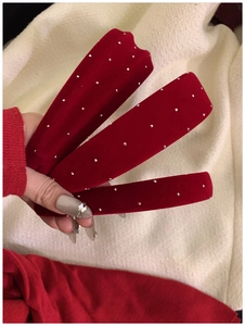 Detail view of red velvet headbands with sparkling rhinestones held by hand
