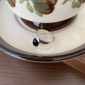 Detail of 925 sterling silver open ring with black oval onyx on vintage ceramic tray