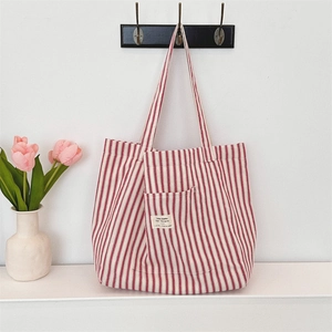 Detail of red and white striped canvas tote bag hanging on a wall with tulips