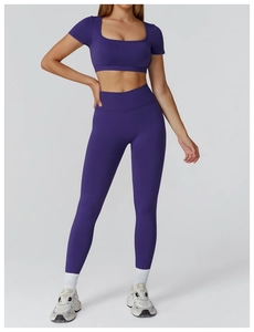 Full-body view of a deep purple seamless yoga set with high waist leggings and short sleeves