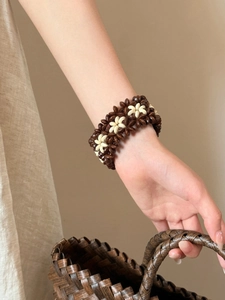 Detail of wide bohemian beaded bracelet featuring brown and white floral daisy patterns