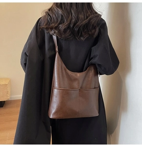 Model view of large brown PU leather tote bag with two front pockets on shoulder