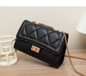 Detail of black quilted crossbody bag featuring a gold chain strap and square metal clasp