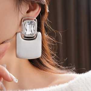 Close-up of elegant silver rectangle earrings with large crystals on model