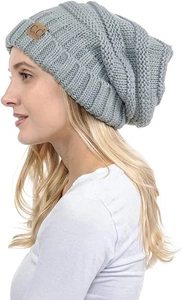 Detail of light grey cable-knit beanie featuring a brown leather C.C brand label