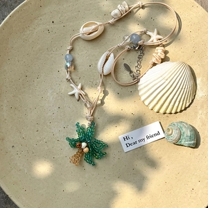 Gros plan sur un collier de plage avec pendentif palmier et coquillages