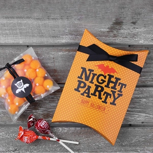 Halloween pillow gift box with orange polka dots and candy on a rustic wooden background