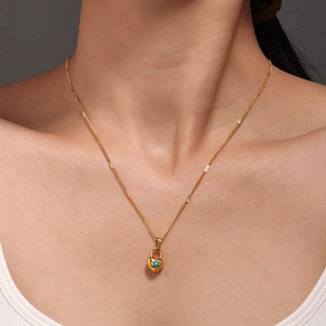 18k gold plated stainless steel heart lock necklace with turquoise stone on a woman's neck