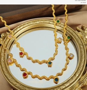 Close-up of golden wavy chain necklace featuring colorful heart and star zircon charms